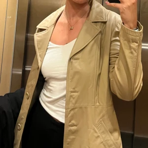 Beige skinnjacka från Janbell - Snygg beige skinnjacka från Janbell med klassisk krage och knappar framtill, djupa fickor och slits i bak ⚡️ liknande jackor säljes second hand för mellan 500-1000 på Sellpy, mitt pris 350 💓
