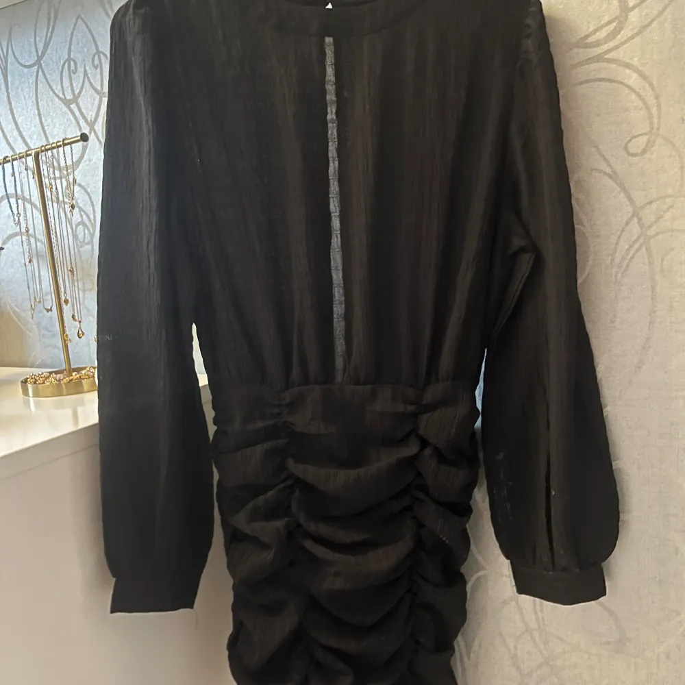 Elegant svart klänning med långa ärmar och rynkdetaljer längs kjolen. Bara använd 2 gånger och är därför i nyskick!🤩. Mekot.