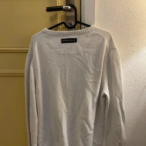 Vit tröja från Morris - Säljer en stilren vit tröja från Morris med svart text och korsade pilar på framsidan. Tröjan har långa ärmar och en rund halsringning. Perfekt för en avslappnad och snygg look.