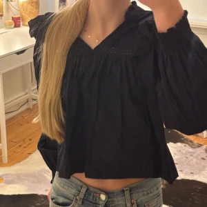  Långärmad blus - En mörk blå blus med långa armar. Den fina detaljer och volanger vid axlarna. Passar perfekt att både klä upp och ner.