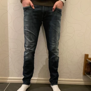 Replay Anbass  - Här har vi ett par riktigt snygga replay jeans med lite slitningar på knäna som ser väldigt bra ut. Byxorna är i storlek W33, L32 och modellen på bilden är 1,80cm och väger 65kg. 