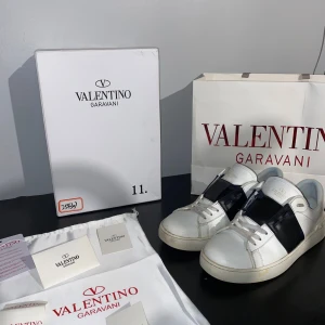 Valentino open - Snygga Valentino Garavani sneakers i vitt med en bred svart rem över snörningen. Perfekta för en stilren look. SKRIV VID INTRESSE OCH HÖR AV DIG OM DU VILL KÖPA SKORNA! Fråga om ni vill ha fler bilder eller annat!