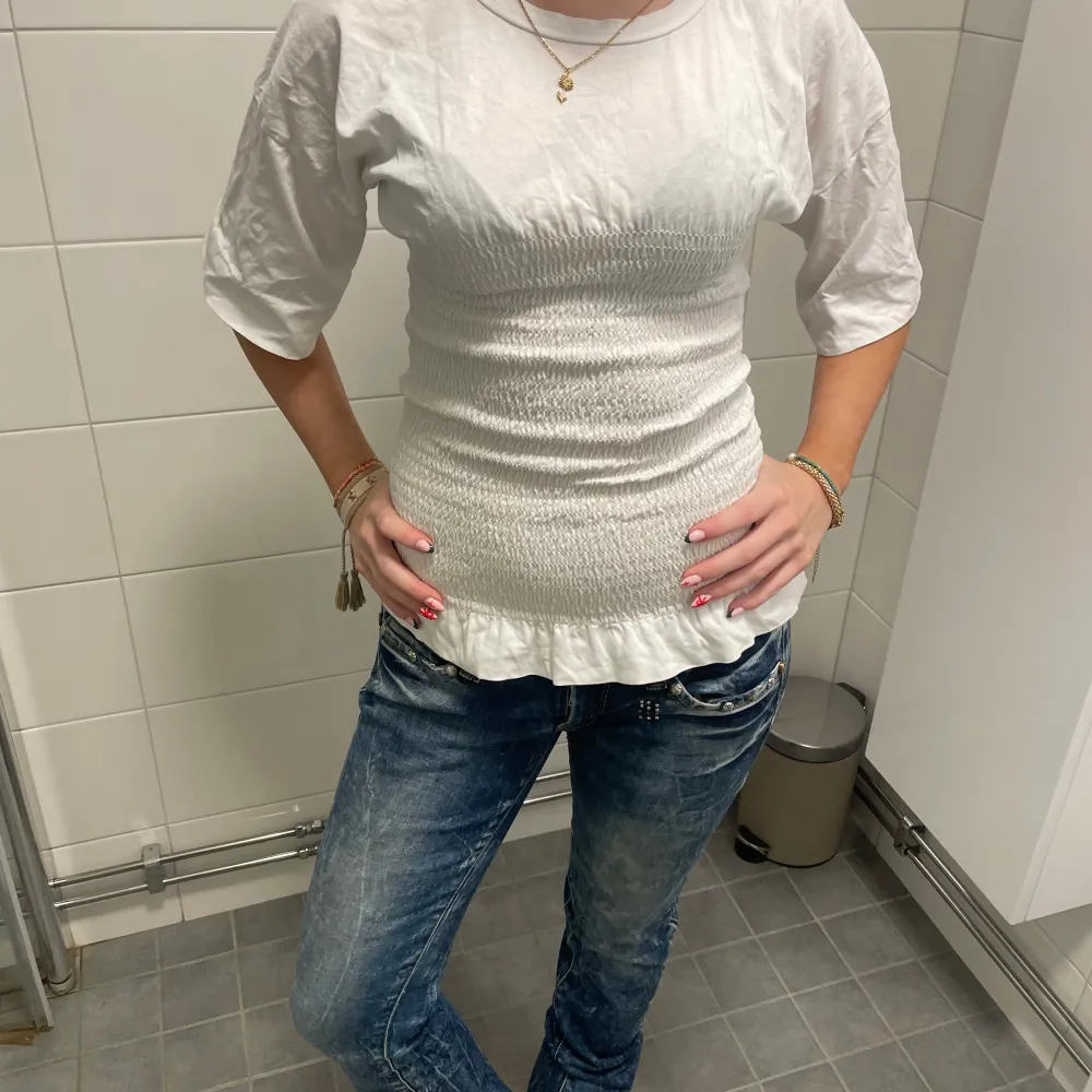 Säljer en stilren vit smock topp med trekvartsärm och smockdetaljer som ger en figurnära passform. Perfekt för en avslappnad men ändå elegant look. Passar bra till jeans eller kjol.❤️❤️. Yläosat.