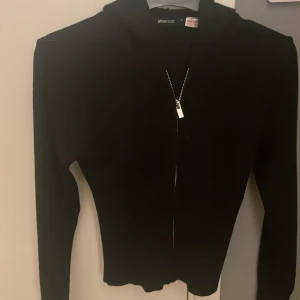 Svart tröja med dragkedja från Gina Tricot - Snygg svart tröja från Gina Tricot med dragkedja framtill. Perfekt för en stilren look. Tröjan har långa ärmar och en enkel design som passar till det mesta.