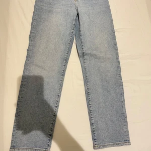 Ljusblå mom jeans i storlek M - Säljer ett par ljusblå mom fit jeans i storlek M. De har en straight passform och är perfekta för en avslappnad stil. Jeansen har klassiska fem fickor och stängs med dragkedja och knapp. Perfekta för både vardag och fest!