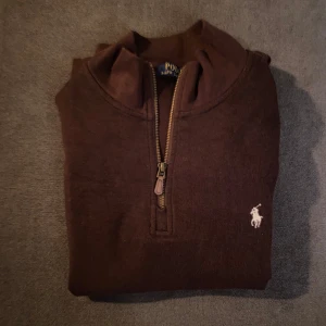 Brun half-zip tröja från Polo Ralph Lauren - Säljer en snygg brun half-zip tröja från Polo Ralph Lauren. Den är varm och har en bekväm passform. Den är storlek L men passar som M. Materialet är manchester liknande. Nypris: 1500kr, mitt pris: 499kr. Skriv om ni har några frågor!