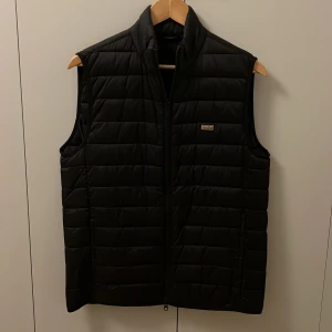 Väst från Barbour  - Snygg svart väst från Barbour i storleken S. Den är knappt använd i nyskick. Säljer den för att den aldrig används. Den är köpt på Care of Carl för 1899 kr. Skriv vid minsta fundering!