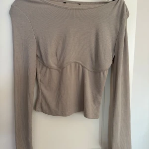 Beige ribbad långärmad topp - Säljer en superfin beige ribbad topp med långa ärmar. Den har en snygg passform och är perfekt för både vardag och fest. Toppen är i mycket bra skick och passar perfekt till höstgarderoben.