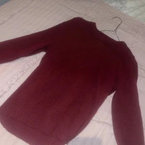 Vinröd fleece tröja - Mysig vinröd tröja i fleece-material, perfekt för kyliga dagar. Den har en enkel design med långa ärmar och en bekväm passform. Perfekt för både vardag och avslappnade tillfällen. Håll dig varm och stilren i denna sköna tröja!