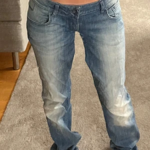 Blå jeans från Cross - Säljer ett par blå jeans från Cross. De har en låg midja och en straight passform. Jeansen har en slitning mellan benen men går att sy därav priset.