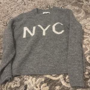 Säljer en mysig grå tröja från Primark med vit text 'NYC' på framsidan. Tröjan har långa ärmar och är perfekt för kyligare dagar. Enkel och stilren design som passar till det mesta.