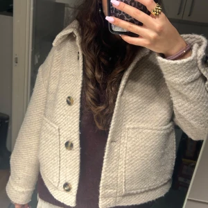 Beige quiltad jacka - Säljer en superfin beige quiltad jacka med stora knappar. Den är perfekt för höst och vår, och har en normal passform. Jackan är i mycket bra skick och har långa ärmar. Perfekt för att hålla stilen när det är lite kyligt ute! 