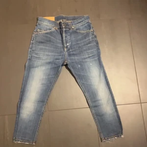 Blå jeans med slitna detaljer - Säljer ett par snygga blå jeans i bra skick med coola slitna detaljer och fransar vid bensluten. Perfekta för en avslappnad stil. De har en klassisk femficksdesign och en bekväm passform.