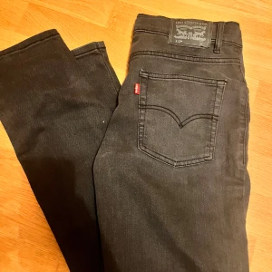 Svarta jeans från Levi's - Säljer ett par snygga svart/gråa jeans från Levi's i mycket bra skick. De har en klassisk femficksdesign och en bekväm passform. Perfekta för både vardag och fest! 🖤