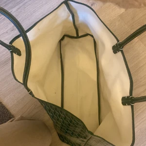 Grön shoppingväska  - Säljer en snygg grön shoppingväska med ett fint mönster . Väskan är rymlig och perfekt för shoppingturer eller som en stilren vardagsväska. Den har två handtag och är i mycket bra skick. Passar perfekt för både vardag och speciella tillfällen. Pris kan diskuteras. Har jätte små fläckar på insidan men ingenting som märks överhuvudtaget 