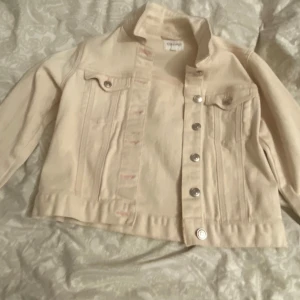 Beige jeansjacka från Forever 21 - Säljer en snygg beige jeansjacka från Forever 21 i bra skick. Jackan har en klassisk design med silverfärgade knappar och två bröstfickor. Perfekt för vår och sommar, och funkar både till vardags och fest. Storleken är dam M och passformen är normal.