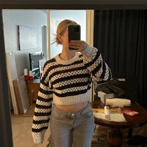 Randig stickad tröja - Säljer en superfin randig stickad tröja i svart och vit. Den är croppad och har en mysig, oversized passform med långa ärmar. Håller ju tyvärr inte värmen med tanke på mönstret men är helt perfekt till sena sommarkvällar 