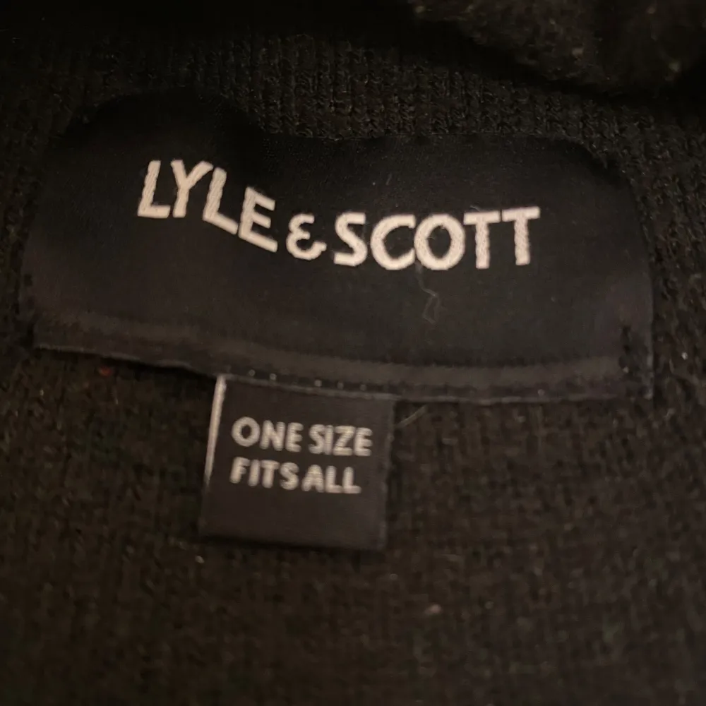 Snygg svart mössa från Lyle & Scott med deras ikoniska gula logga framtill. Perfekt för att hålla värmen under kalla dagar. Den är i one size och passar de flesta. Stilren och enkel design som funkar till alla outfits. 🖤. Accessoarer.