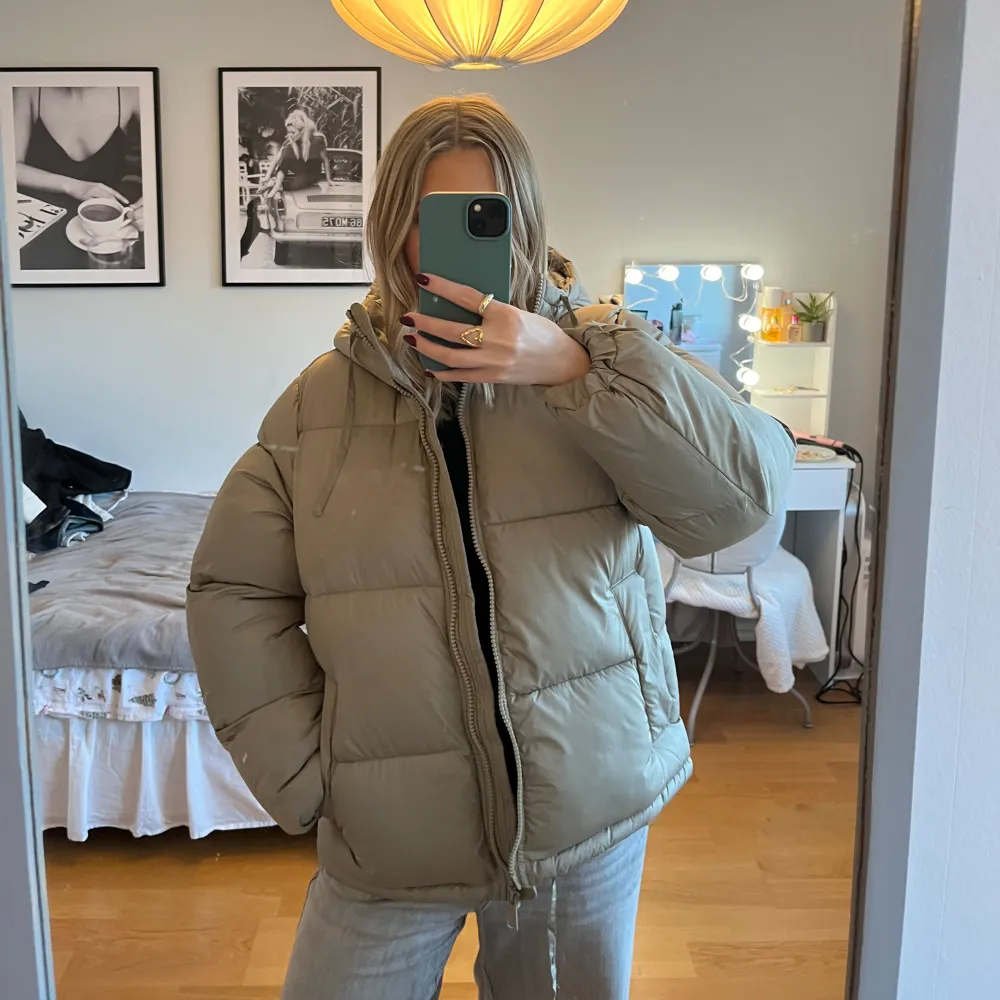 Säljer en grön pufferjacka från H&M med huva och dragkedja. Jackan är perfekt för kyliga dagar och har en bekväm passform. Den är långärmad och har en stilren design. Sitter oversized.. Takit.