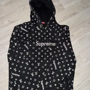 Säljer en svart hoodie med det ikoniska Supreme x Louis Vuitton-mönstret. Den har en stor logga på bröstet och är perfekt för streetwear-stilen. Hoodien är i bra skick och har en bekväm passform. Perfekt för höst och vinter!