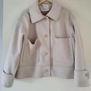 Beige kappa från Kappahl - Snygg beige kappa från Kappahl med stora fickor och knappar framtill. Perfekt för höst och vår. Kappan säljs inte längre i denna färg. Nypris 899kr🩷