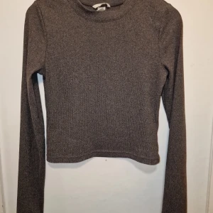 Grå ribbad tröja - Säljer en stilren grå ribbad tröja med långa ärmar. Tröjan har en enkel design med rund halsringning. Garderobsrensning så kika gärna in övriga auktioner.