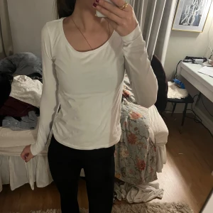 Vit långärmad topp - Säljer en stilren vit långärmad topp med rund halsringning. Perfekt för lager-på-lager eller som den är. Passar till många olika outfits och tillfällen.