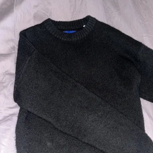 Svart stickad tröja från Jack & Jones - Säljer en stilren svart stickad tröja från Jack & Jones. Perfekt för kyliga dagar med sin mjuka och bekväma passform. Tröjan har en klassisk rund hals. Storleken är M