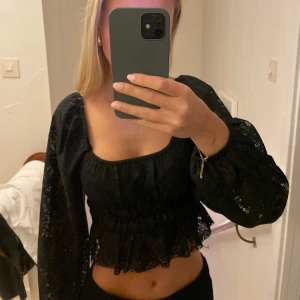 Svart blus med volangdetaljer - Snygg svart blus med volangdetaljer och långa ärmar. Perfekt för en stilren look med en touch av elegans. Blusen har en smickrande passform och är lätt att matcha med olika outfits.