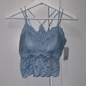 Ljusblå spetslinne från Miss Nora - Säljer ett ljusblått spetslinne från Miss Nora med smala axelband och vacker spetsdetalj. Linnet har en fin passform och är både stilrent och bekvämt. Super fin festtopp som även är vadderad.