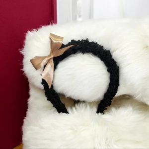Svart diadem med rosett - Elegant svart diadem med en fin beige rosett. Perfekt för att ge en stilfull touch till din outfit. Diademet är knuten med makramé med svart teddygarn. Matchande hårband ingår.