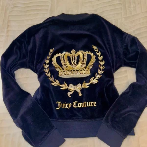 Supersnygg zip up från Juicy Couture - Säljer den här supersnygga zip upen från Juicy Couture med en glittrig krona och logga på ryggen. Jackan har en dragkedja framtill och långa ärmar. Perfekt för en glamorös look! Storlek är 12 på barn men motsvarar XS på vuxen. Mycket bra skick, bara en defekt på sista bilden men inget man märker vid användning. 