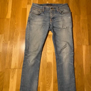 Nudie jeans Grim Tim - Snygga blå jeans från Nudie Jeans med en klassisk straight passform. De har en lätt slitning på framsidan och är tillverkade i högkvalitativt denim. Trendiga och efterlängtad wash, perfekt nu till våren. Ifall mer frågor eller bilder skriv gärna! Mvh!