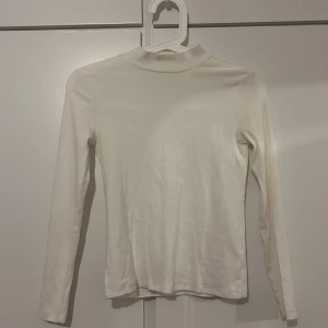 Vit långärmad polotröja från H&M - Säljer en stilren vit långärmad polotröja från H&M i ekologisk bomull. Perfekt för lager-på-lager under kyligare dagar. Enkel och tidlös design som passar till det mesta. 🌟