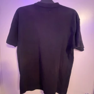 Svart t-shirt med tryck - Snygg svart t-shirt med ett unikt tryck på framsidan den är lite skador från solen som gör att den är lite brun vid kragen annars är de 7/10 storlek xs men den är oversized så den passar M 
