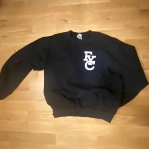 Svart sweatshirt med tryck - Säljer en svart sweatshirt med ett vitt tryck på bröstet. Tröjan har långa ärmar och en rund halsringning. Perfekt för en avslappnad stil.