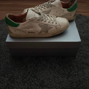 Vita golden gose sneakers med gröna detaljer. Öppen för bud !!! Över 1000kr - Snygga vita sneakers med gröna hälpartier och en stjärndetalj på sidan. Skorna har snörning och en klassisk design som passar perfekt för en avslappnad stil.