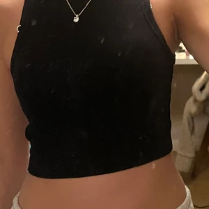 Svart ribbad linnetopp från H&M - Säljer en stilren svart ribbad linnetopp från H&M. Toppen är ärmlös och har en tight passform, perfekt för en trendig look. Passar bra till både jeans och kjol.