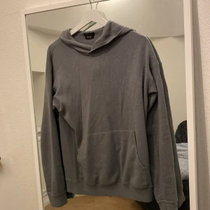 Grå hoodie från Massimo Dutti - Säljer en stilren olivgrön hoodie från Massimo Dutti i extrafin bomull. Tröjan har en klassisk design med huva och långa ärmar, perfekt för en avslappnad look. Den är mjuk och bekväm, idealisk för kyligare dagar. Inga skador ellee fläckar, funkar för båda kön men passar nog bäst på killar. Med sina rötter i Spanien erbjuder Massimo Dutti stilrena kläder med hög kvalitet i diskreta, jordnära färger.