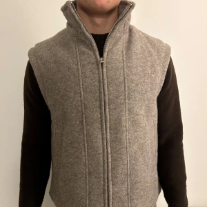 Grå ullväst med dragkedja - Säljer denna gråa väst som aldrig kommit till användning. Köpte den på zara i Paris men då den är stor i storleken har jag aldrig använt den. Storlek är S men som sagt är den ganska stor i storleken!