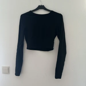 Svart croppad långärmad topp - Säljer en stilren svart croppad topp med långa ärmar. Perfekt för både vardag och fest. Toppen är tight och ger en snygg siluett. Passar bra till både jeans och kjol!💕