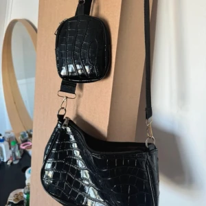 Väska - Jag säljer denna handväska eftersom den inte har kommit till användning på länge. verkligen ganska glänsande färg. den har även ett litet fack som är perfekt att förvara småsaker i