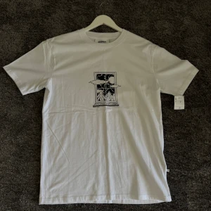 Vit t-shirt från Minimum - Säljer en snygg vit t-shirt från Minimum med ett coolt tryck på framsidan. T-shirten är i nyskick och har korta ärmar. Perfekt för en avslappnad stil!