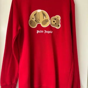 Röd tröja från Palm Angels - Säljer en snygg röd tröja från Palm Angels i storlek XXL men passar som L. Den har ett coolt nallemotiv på framsidan och är gjord av 100% bomull. Perfekt för att sticka ut i mängden med sin unika design. Passar både till vardags och fest!