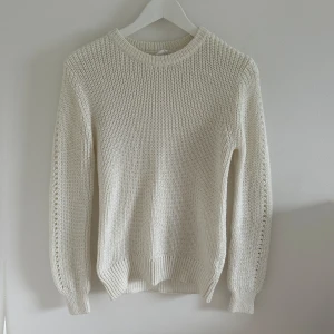Vit stickad tröja - Säljer en superfin vit stickad tröja i storlek XS. Den har långa ärmar med ett hålmönster längs sidorna och ribbade muddar. Aldrig använd.