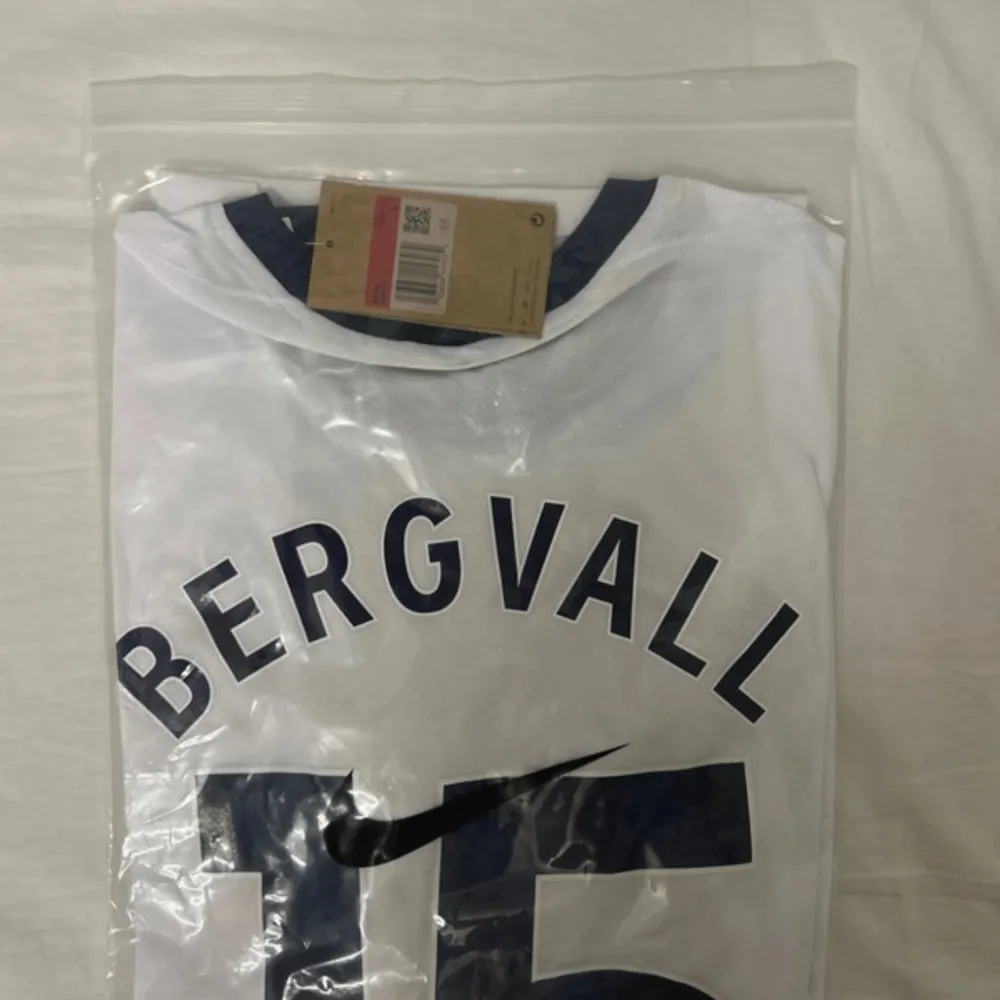 Säljer en vit Tottenham Hotspur fotbollströja från Nike i Dri-FIT material. Tröjan har korta ärmar och mörkblå detaljer. Den är i nytt skick och har 'Bergvall 15' tryckt på ryggen.. T-shirts.