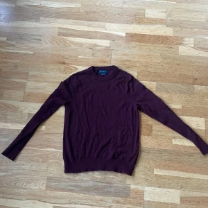 Vinröd merinoulltröja från Riley - Säljer en stilren vinröd tröja från Riley i 100% merinoull. Perfekt för kyliga dagar med sin mjuka och varma känsla. Tröjan har en klassisk design med långa ärmar och rund halsringning. Passar både till vardags och lite finare tillfällen. 🧶Nypris är 899 :-