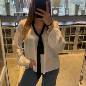 Vit blus med svart knytband - Säljer en stilren vit blus med ett svart knytband i halsen. Storlek 36 från H&M❤️