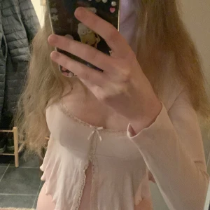 Rosa långärmad topp med volangdetaljer - Säljer en söt rosa långärmad topp med volangdetaljer och knyt framtill. Säljer för att den va lite liten för mig. Tröjan är i xs och väldigt bra skick helt som ny