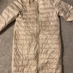 Beige dunjacka från Zara Basic - Säljer en snygg beige dunjacka från Zara Basic i storlek XS. Jackan har en dragkedja framtill och är quiltad för extra värme. Perfekt för kyliga höst- och vinterdagar. Den är i  bra skick och redo för nya äventyr!